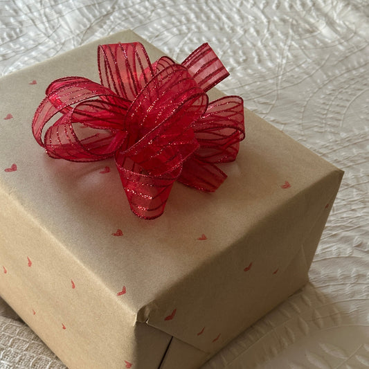 Geschenkverpackung mit Seidenpapier, Schleife oder Blume sowie eine passende Karte